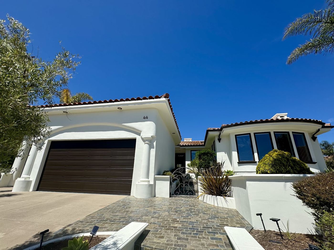 A large white stucco house with a tile roof, freshly painted, with a dark garage door.